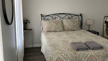 A bedroom with a bed, a ceiling fan, a bedside table, and a nightstand.