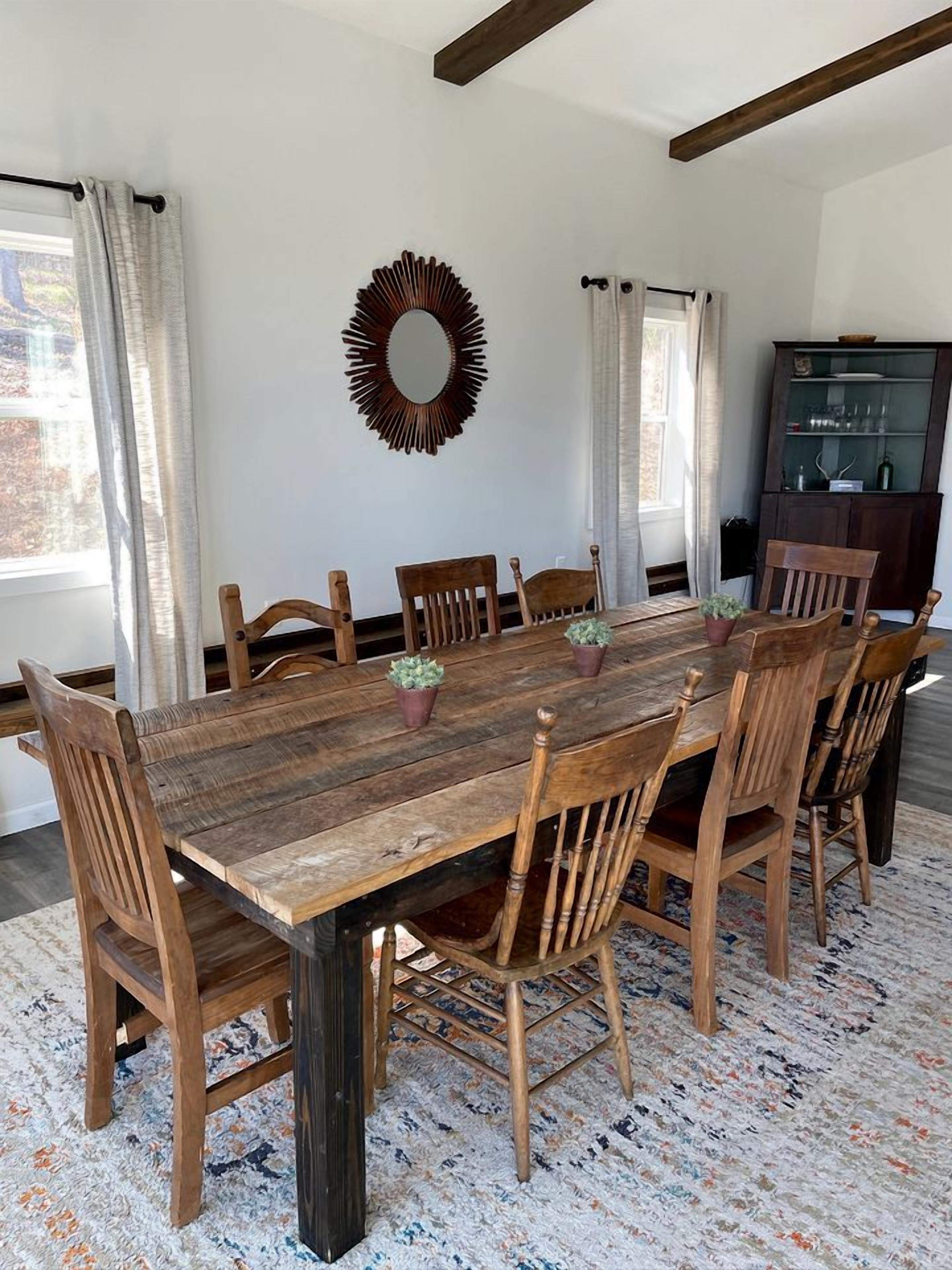 A dining area with a wooden table and chairs, a decorative mirror, and a cabinet with glass doors.