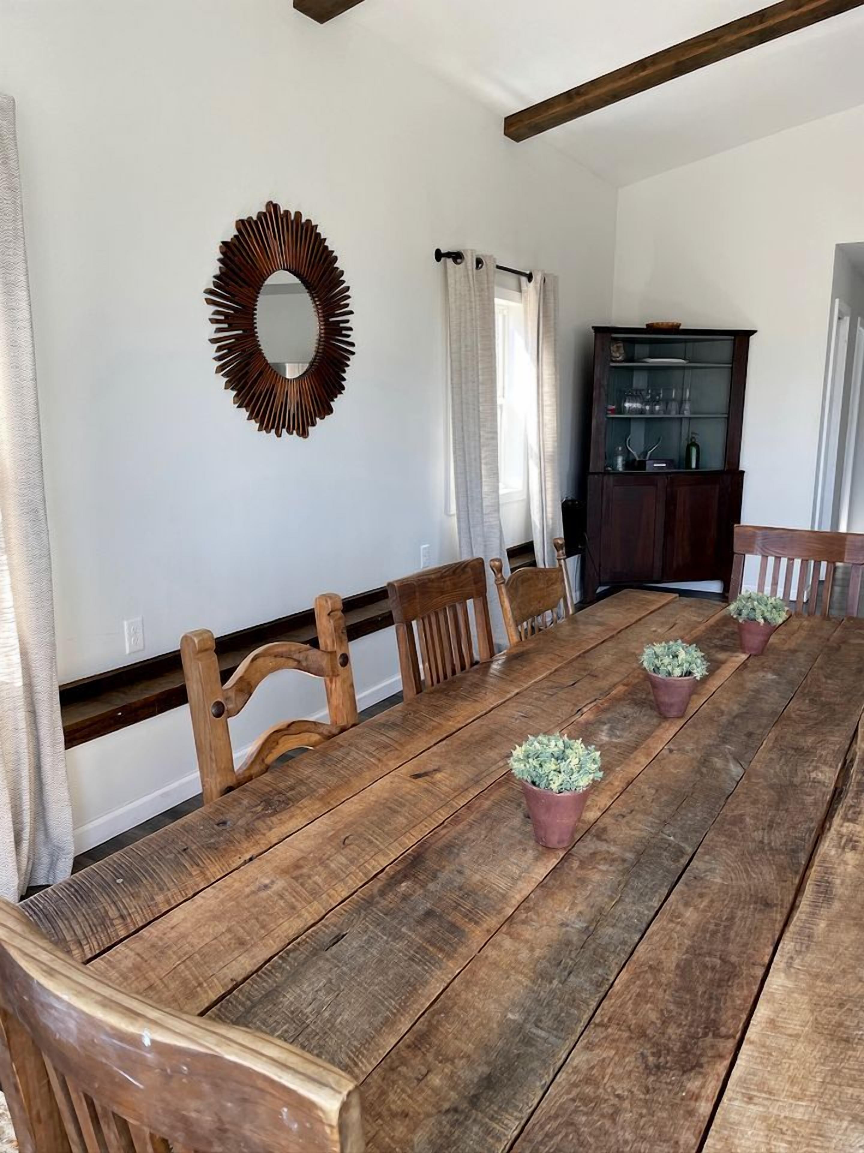 A dining room with a wooden table, chairs, a mirror, and a cabinet.