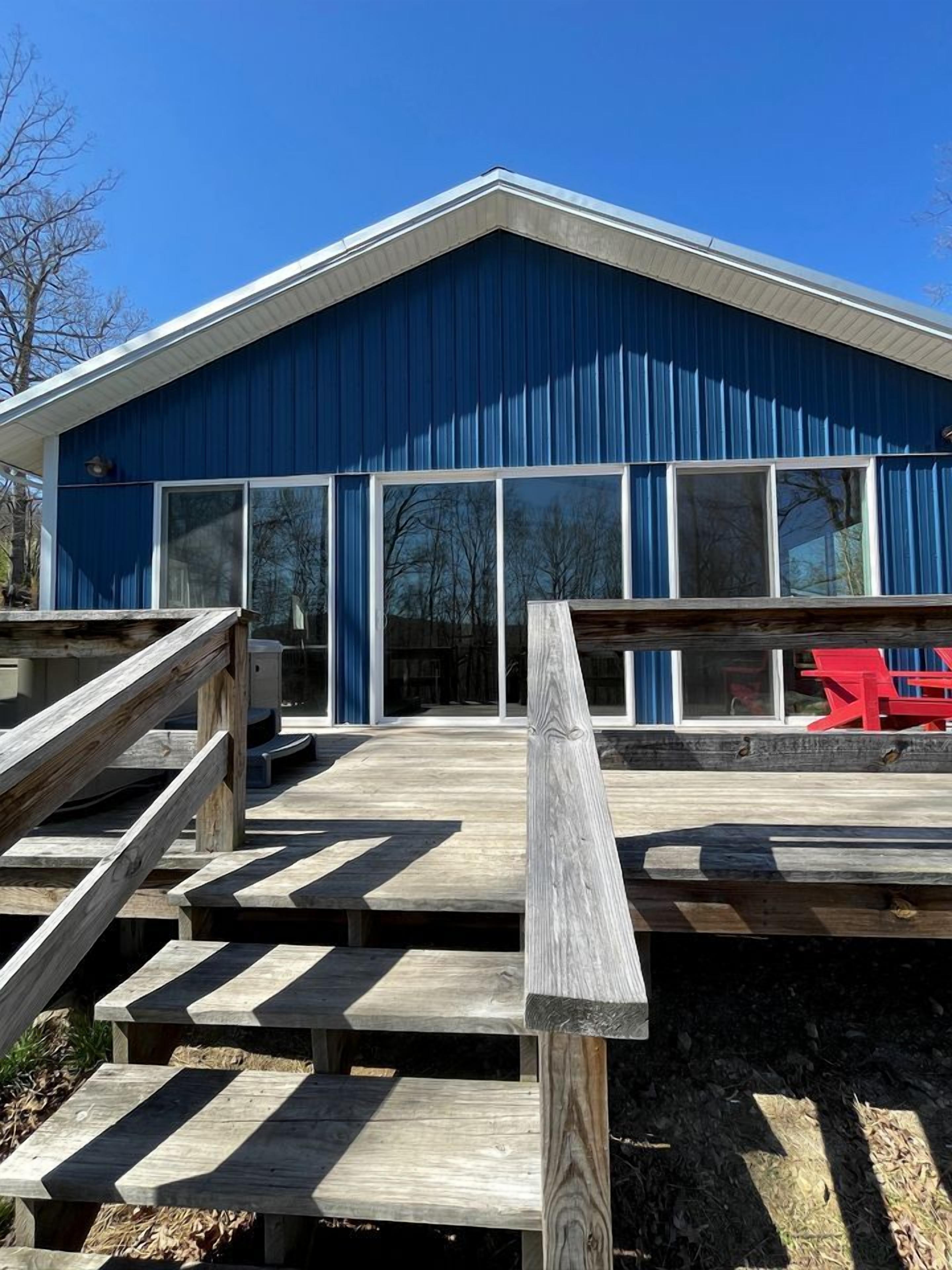 A blue building with large windows and a wooden staircase leading to a deck.
