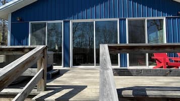 Een blauw gebouw met grote ramen en een houten trap die naar een terras leidt.