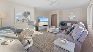 A living room with a sofa, a recliner, a coffee table, a TV, and a beach-themed painting. - Betsy's Batch Family Holiday Home Soldiers Point (Soldiers Point)
