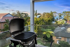 A Weber Q grill on a balcony with a view of a residential area and a body of water. - Betsy's Batch Family Holiday Home Soldiers Point (Soldiers Point)
