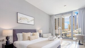 A modern hotel room with a large bed, a view of tall buildings, and a dining area with a table and chairs. - LUX LIV Contemporary Skyline Studio (Dubai)