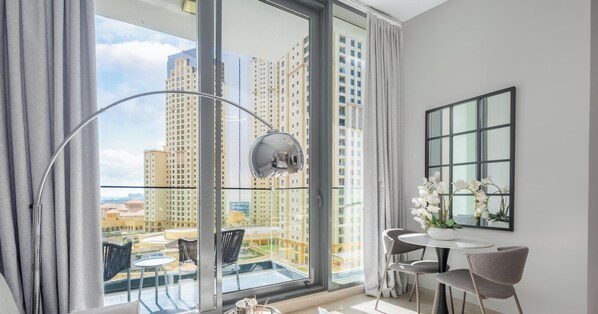 Ein modernes Zimmer mit großem Fenster, einem runden Tisch mit Stühlen, einer Topf-Orchidee und einem Spiegel an der Wand.