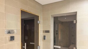 A modern bathroom with a sauna, a steam room, and a shower area. - LUX LIV Contemporary Skyline Studio (Dubai)