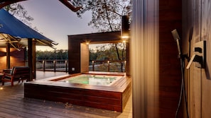 A wooden deck with a hot tub, a bench, and a pergola.