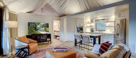 A tented living area with a sofa, chairs, a coffee table, and a TV.