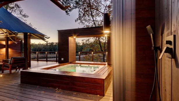 Eine Holzterrasse mit Whirlpool, einer Bank und einer Pergola.