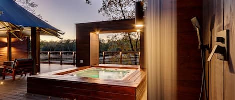 A wooden deck with a hot tub, a bench, and a pergola.