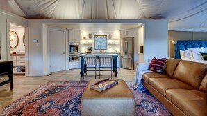 Ein modernes Wohnzimmer mit Ledersofa, einem gemusterten Teppich und einem Essbereich mit Barhocker.