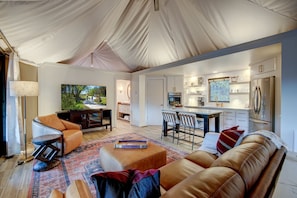A tented living area with a sofa, chairs, a coffee table, and a TV.