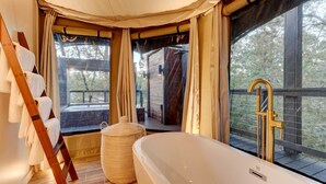 Ein Badezimmer mit Badewanne, einer Holzleiter und einem großen Fenster mit Vorhängen.