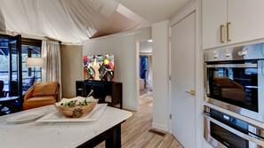 Eine moderne Küche mit einem großen Backofen, ein Essbereich mit einem Marmortisch und ein Fernseher, der ein Pferderennen zeigt.