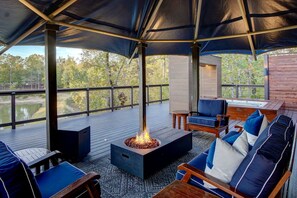 Une terrasse extérieure avec un foyer, des sièges et une vue sur un plan d’eau.