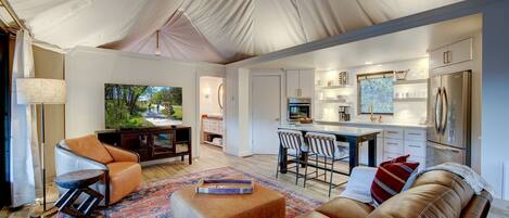 A tented living area with a sofa, chairs, a coffee table, and a TV.