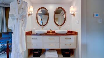 A hotel bathroom with two sinks, a robe rack, and a mirror.