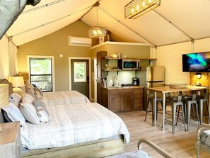 A tented accommodation with a bed, kitchenette, bar area, and a TV. - Texas Glamping Vacation Waterfront Cabin #18 in Marion, TX (Marion)