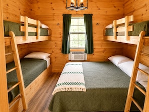 A cabin-style room with two bunk beds, a central bed, and a window with curtains. - Nature Lovers Cabin with Spectacular Views of the Great Smoky Mountains, Tennesse (Cosby)