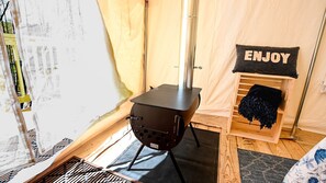 A tent with a portable stove, a 'ENJOY' sign, and a wooden bench.