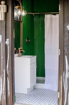 Une salle de bain avec un lavabo blanc, un robinet doré et un mur vert.