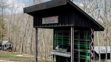 Ein Picknickunterstand mit Grill, umgeben von Bäumen.