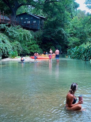 Un río con gente haciendo kayak y nadando, rodeado de abundante vegetación.