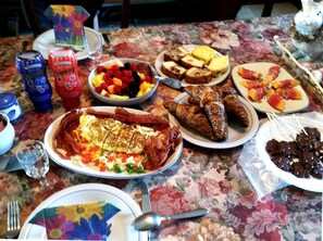 Une table dressée avec divers plats, des condiments et une nappe à motifs floraux.