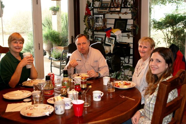 A dining table with plates, cups, and condiments, surrounded by chairs.