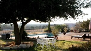 Ein Garten mit Pool, weißem Tisch und Stühlen, einer Liege und einem großen Baum.