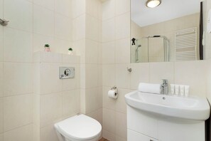 A bathroom with a toilet, sink, and mirror. - Air-conditioned apartment in Wladyslawow | Parking | Balcony (Władysławowo)