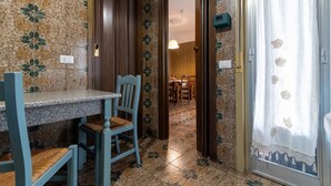 Ein Zimmer mit Esstisch und Stühlen, einer Tür zu einem anderen Raum und einer Wand mit Muster.
