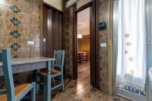Ein Zimmer mit Esstisch und Stühlen, einer Tür zu einem anderen Raum und einer Wand mit Muster.