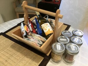 A wooden crate with a bottle, packaged food, and jars labeled with various fruits.