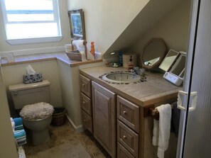 A bathroom with a toilet, sink, and vanity with drawers.