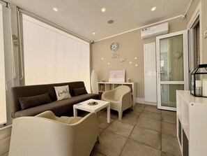 Ein modernes Wohnzimmer mit einer Couch, zwei Sesseln, einem kleinen Tisch und einer dekorativen Wanduhr.