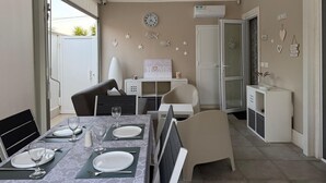 A dining area with a table set for four, a white cabinet, a clock on the wall, and a door leading to another room. - Casa Amare by Geco Vacation Rentals (Agnone)