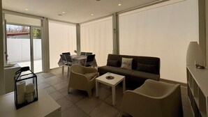 A modern living room with a sofa, two armchairs, a small table, and a dining table with chairs. - Casa Amare by Geco Vacation Rentals (Agnone)