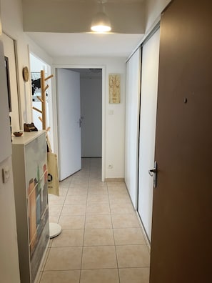 A hallway with a coat rack, a door with a handle, a wall-mounted light fixture, and a tiled floor. - Apartment Avignon 3 rooms 70m2 Private parking (Avignon)
