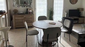 A modern living room with a round dining table, two chairs, a TV, and a decorative mirror. - Apartment Avignon 3 rooms 70m2 Private parking (Avignon)