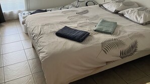 A bedroom with a bed, a window with blinds, a wall-mounted shelf with items, and a painting. - Apartment Avignon 3 rooms 70m2 Private parking (Avignon)