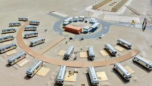 Vista aérea de un estacionamiento con varios autobuses y un edificio central.