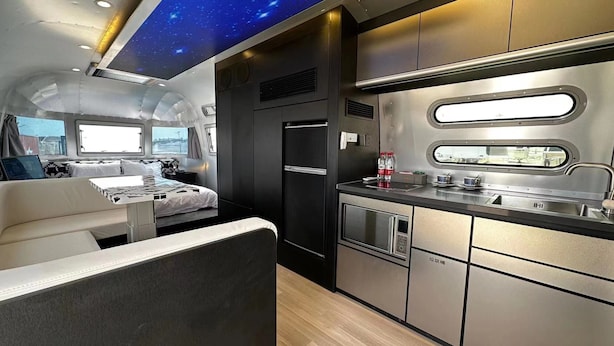 Un interior compacto y moderno con kitchenette, una cama y una zona de estar.
