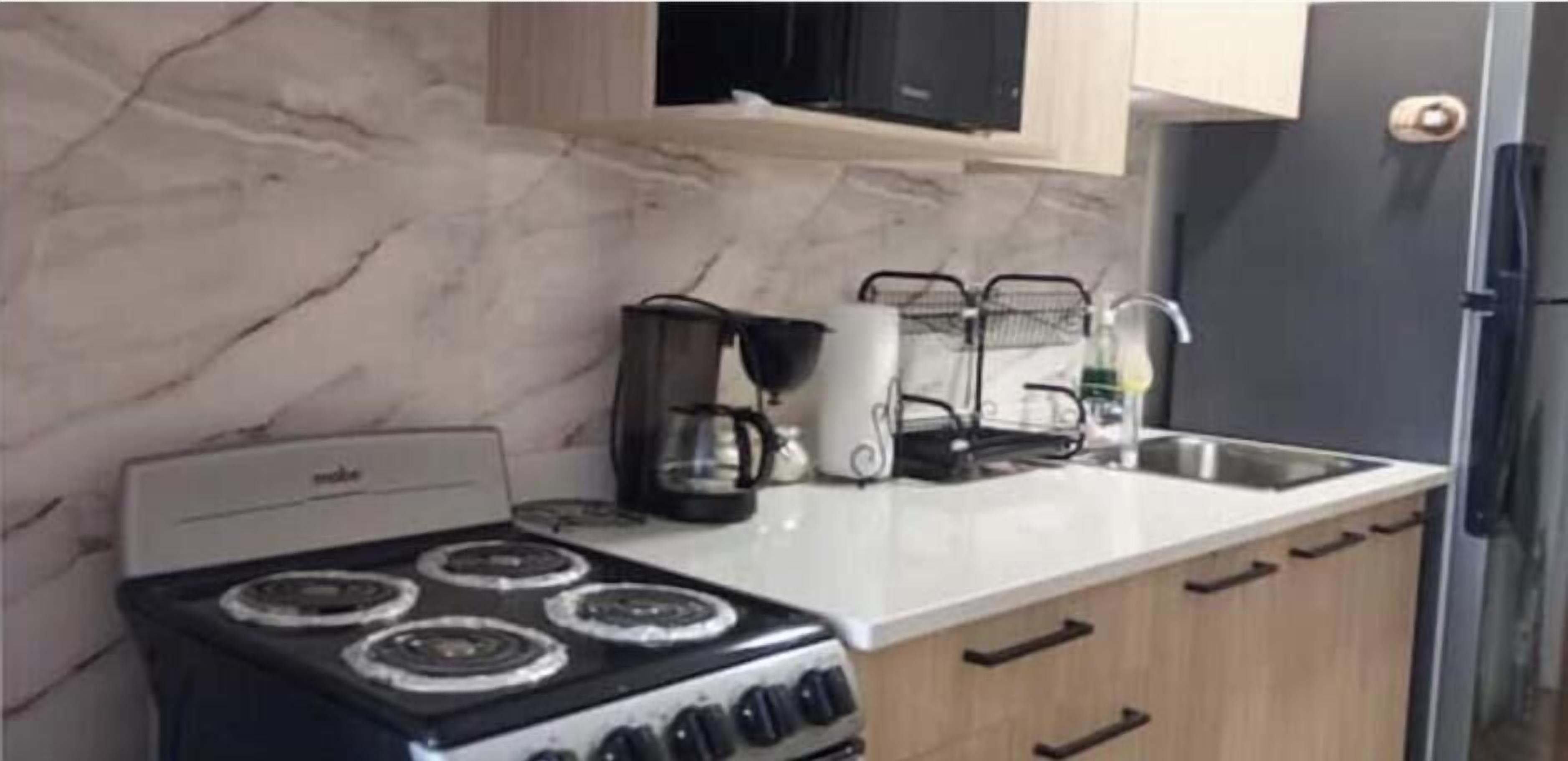 Uma cozinha com fogão, micro-ondas e máquina de café no balcão.