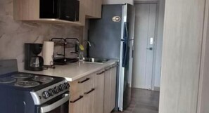 A kitchen with a stove, sink, and refrigerator.