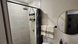 Un bagno con doccia, WC, lavandino e specchio.