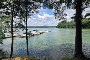 A lake with boats docked, surrounded by trees and a distant shoreline. - Lake Wallenpaupack Condo, Great for All Seasons! (Greentown)