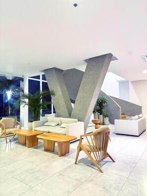 Ein modernes Interieur mit einem weißen Sofa, Holztischen und einer einzigartigen, geometrischen Deckenkonstruktion.