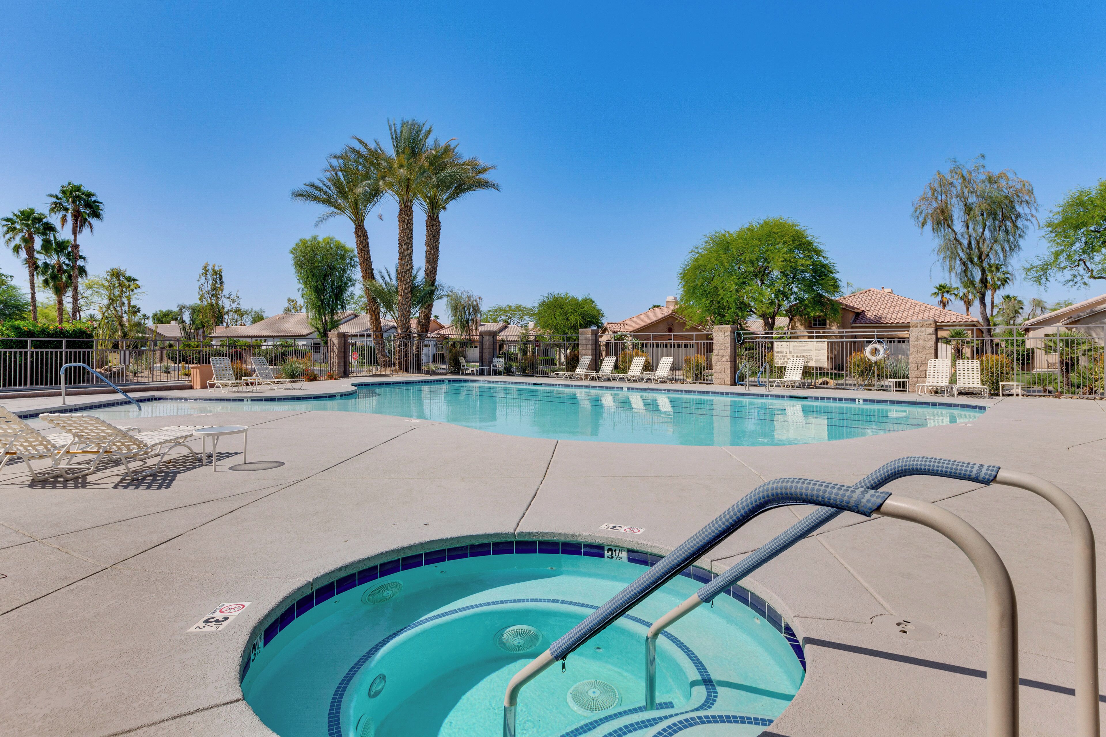 A swimming pool with lounge chairs and palm trees.