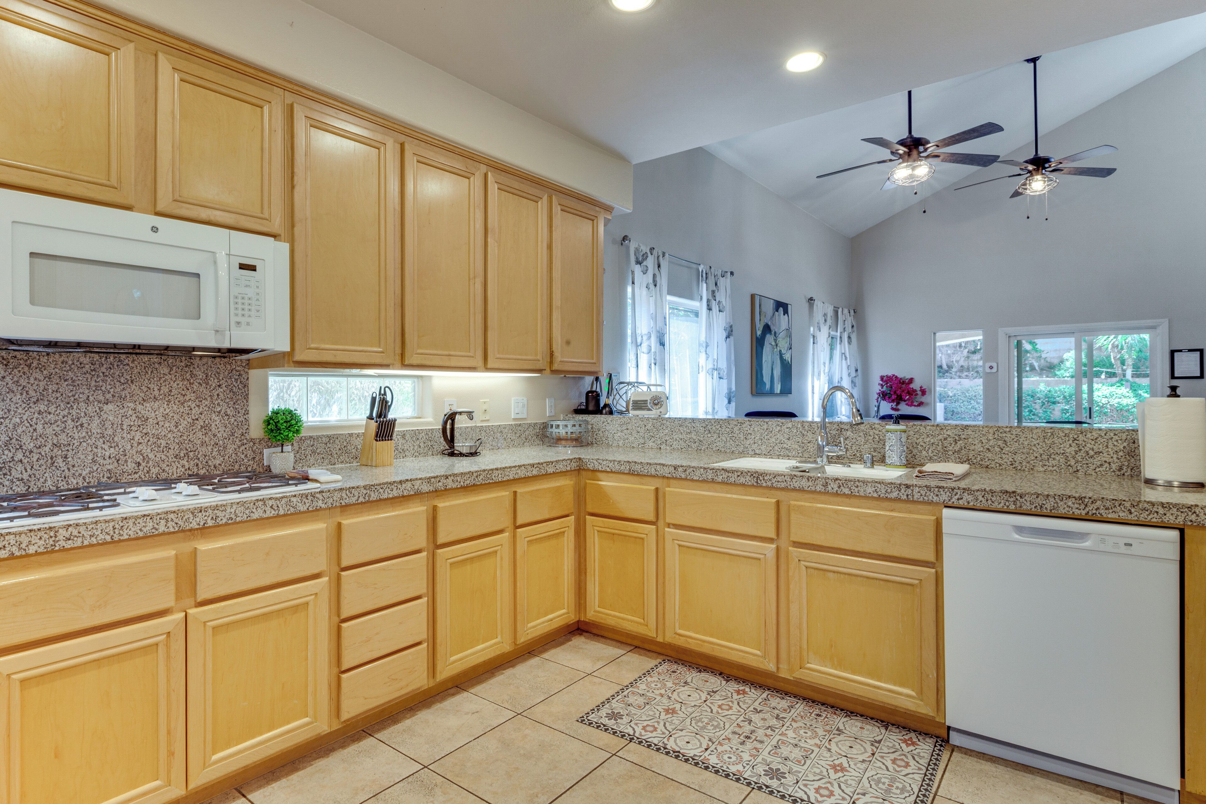 A kitchen with wooden cabinets, a microwave, a dishwasher, and a ceiling fan.
